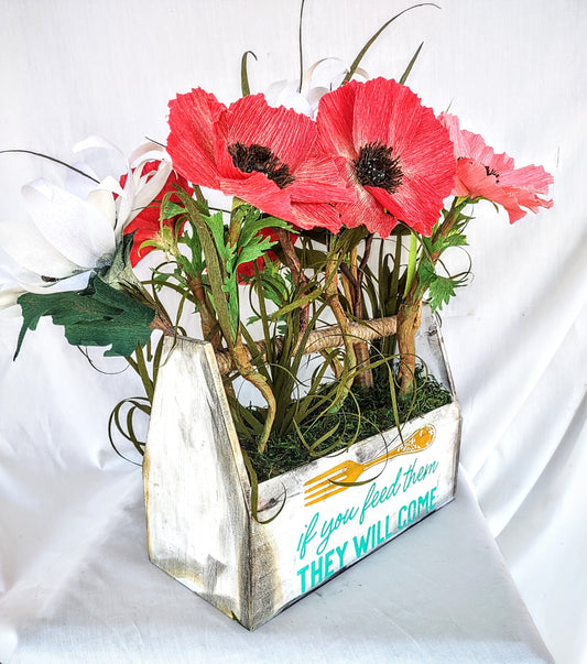 Rustic wooden tool box used as a vessel to place handcrafted Red Poppies and White Sunflower's by using crepe paper. A gift that was given to the Manager in charge of the project from Artisan's Studio. 